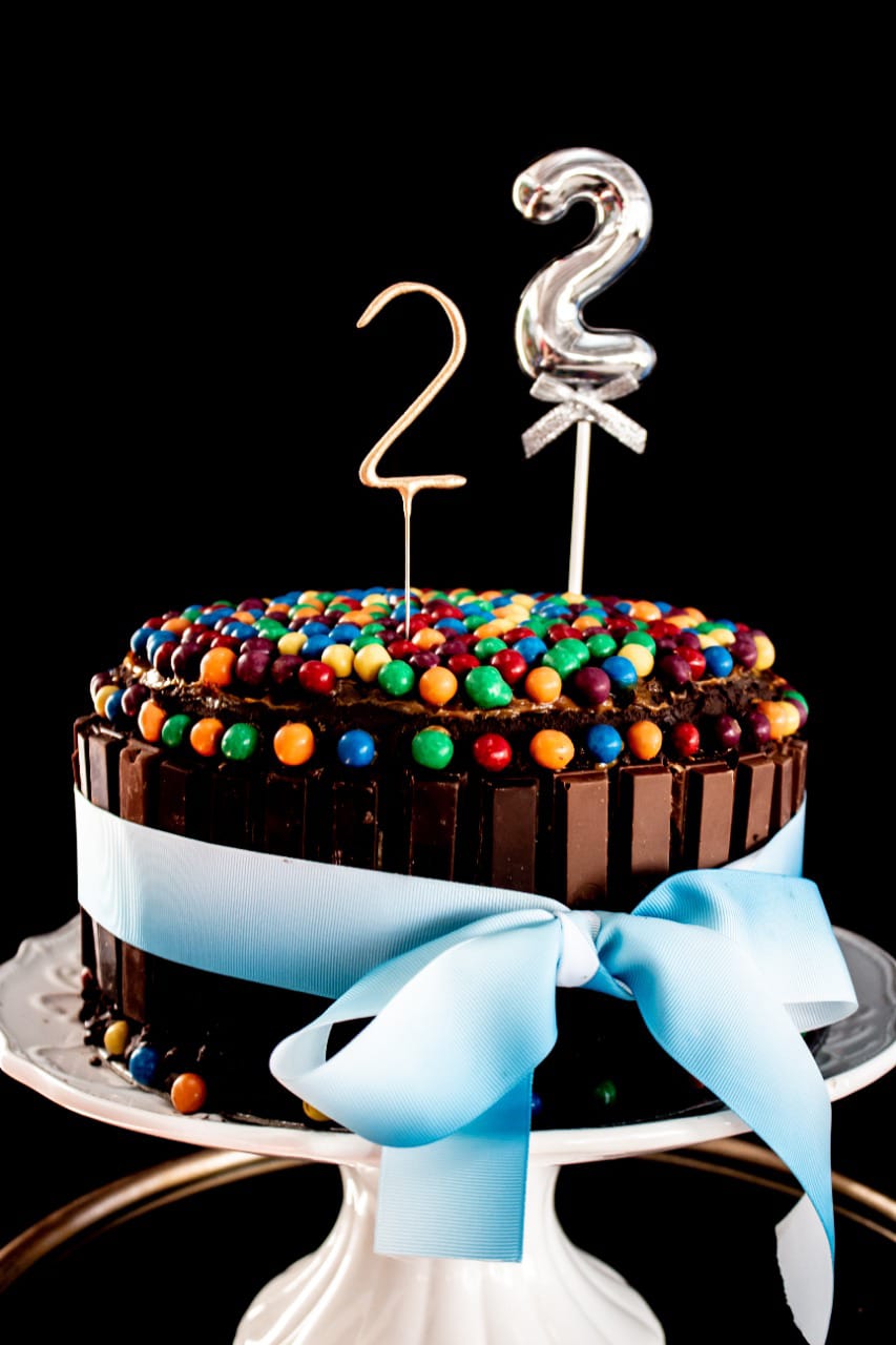 Chocolate birthday cake with colorful candies and blue ribbon