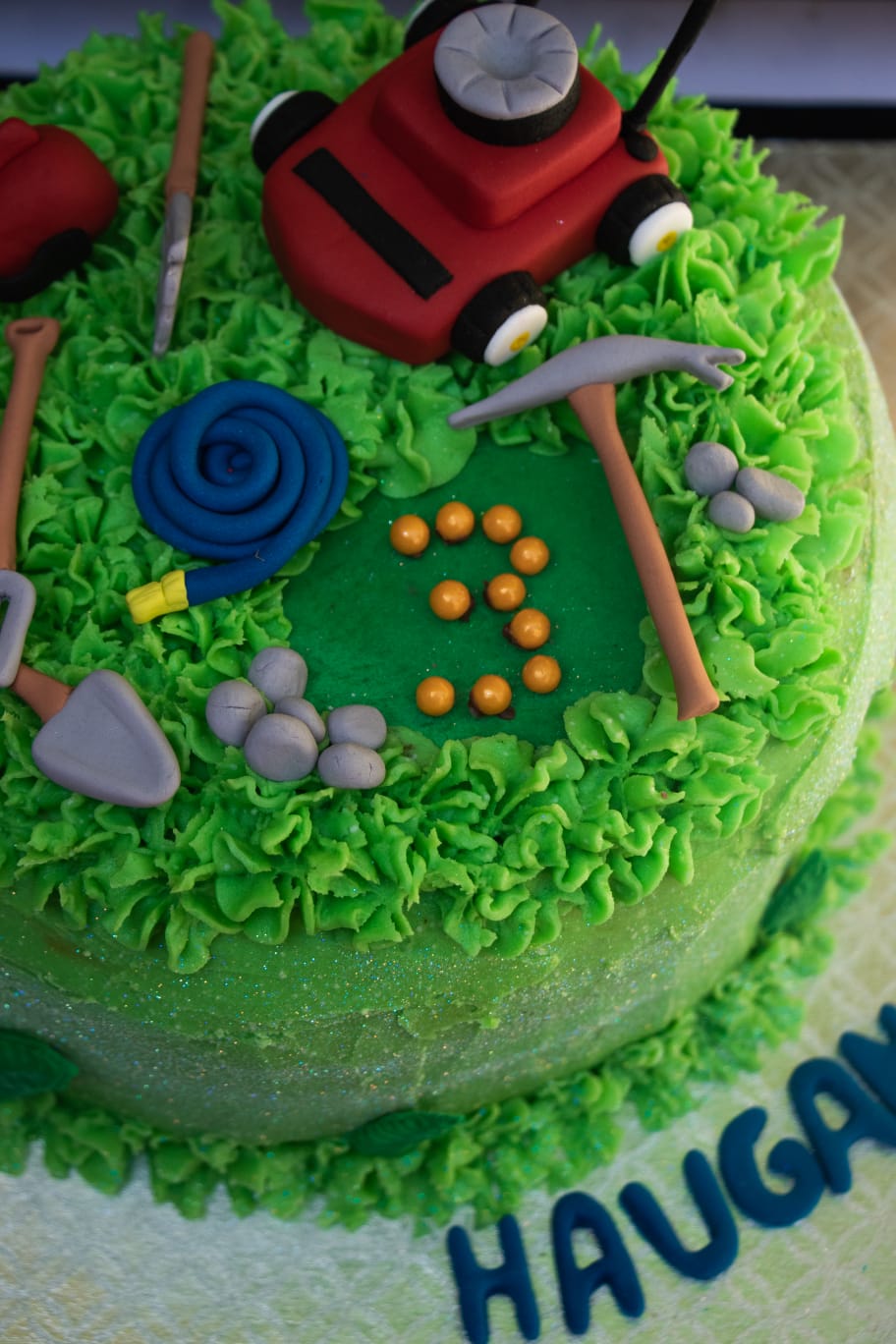Garden-themed cake with lawnmower and green frosting grass